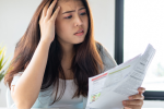Woman with a concerned look holding a stack of bills